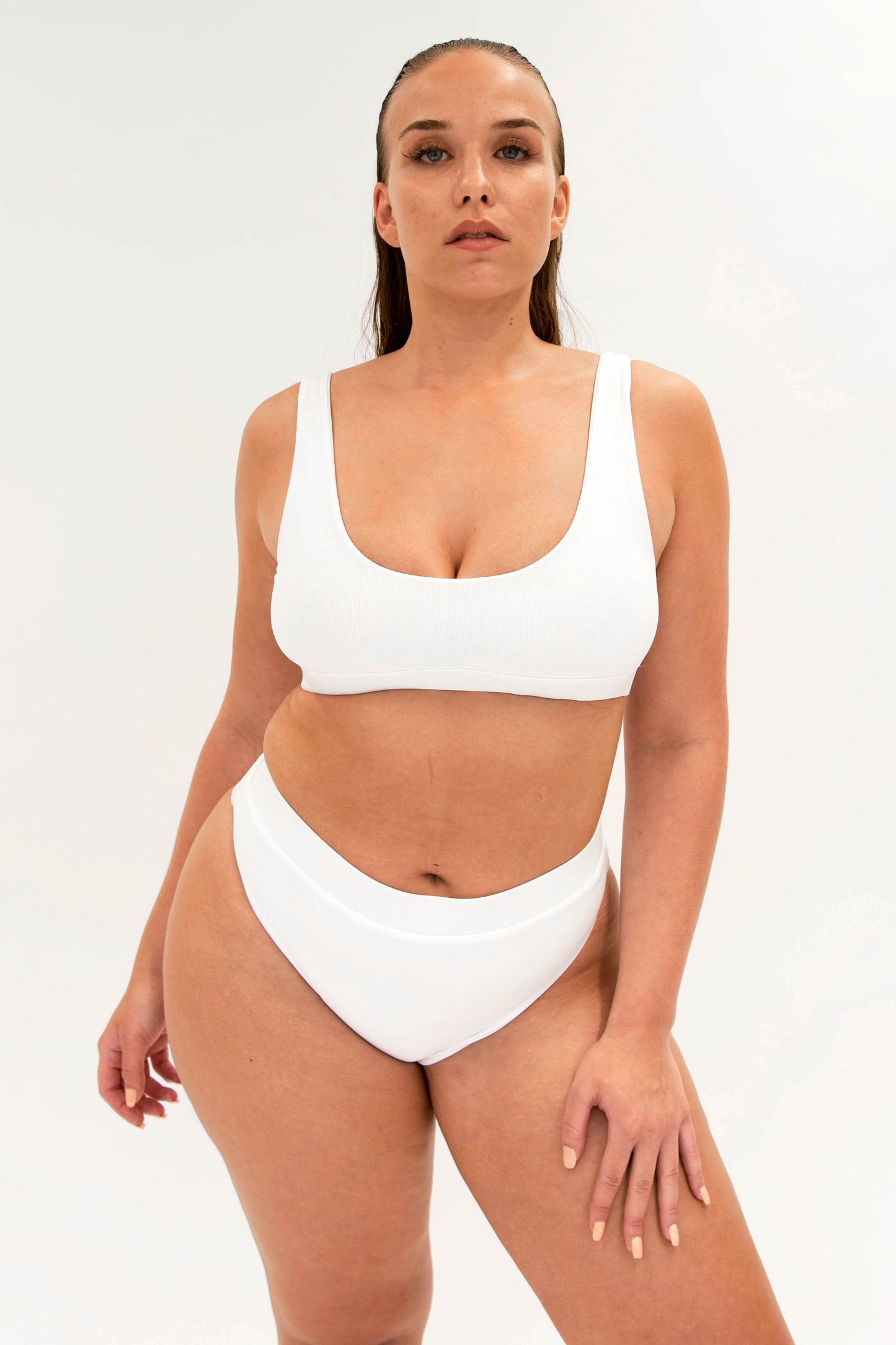 model with white sustainable high cut bikini bottom and sporty top 