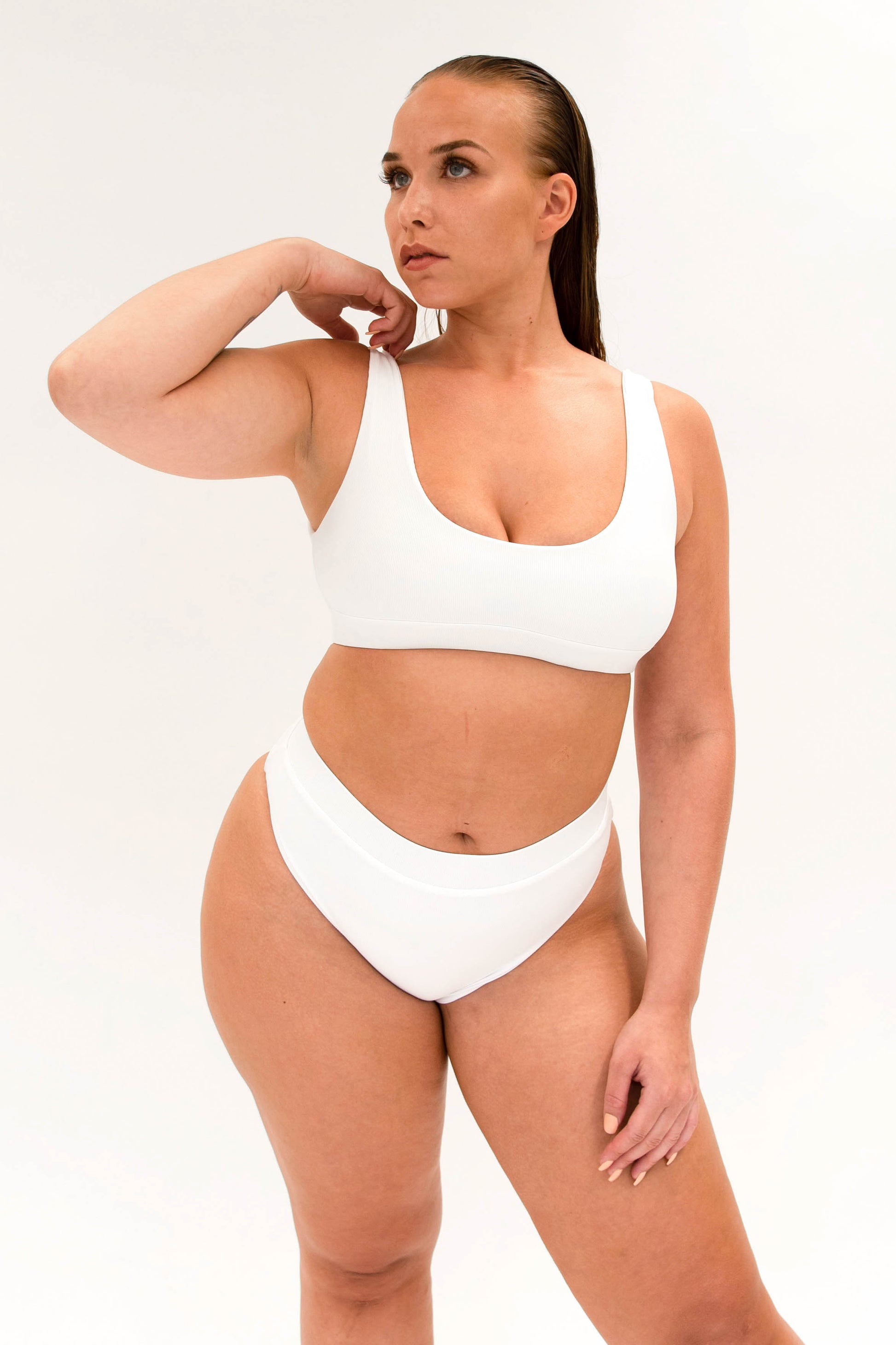 model with white sustainable high cut bikini bottom and sporty top 